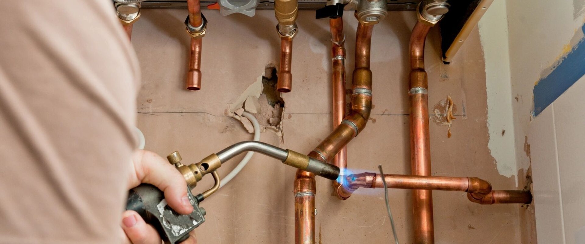 Professional plumber soldering copper pipes on water heater installation in Central Texas